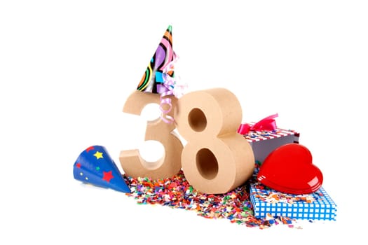 Number of age in a colorful studio setting with paper party hats, a red heart and gifts on a bottom of confettie