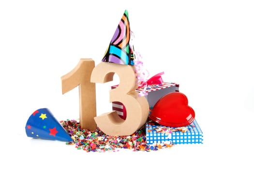 Number of age in a colorful studio setting with paper party hats, a red heart and gifts on a bottom of confettie