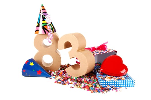 Number of age in a colorful studio setting with paper party hats, a red heart and gifts on a bottom of confettie