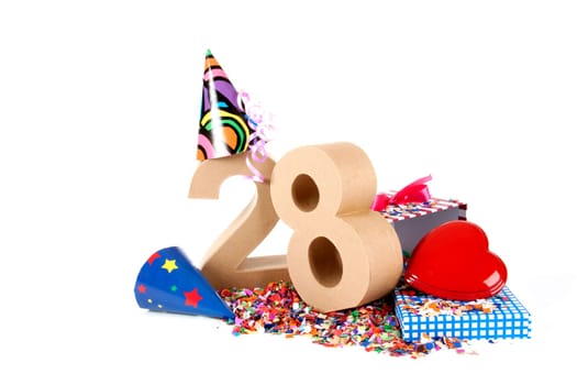 Number of age in a colorful studio setting with paper party hats, a red heart and gifts on a bottom of confettie