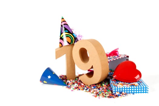 Number of age in a colorful studio setting with paper party hats, a red heart and gifts on a bottom of confettie