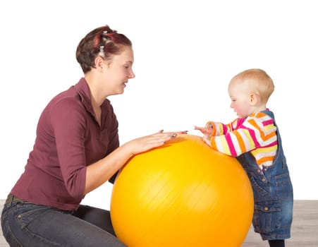 Mother encouraging her young toddler, who has delayed motor activity disability, to stand using a gym ball