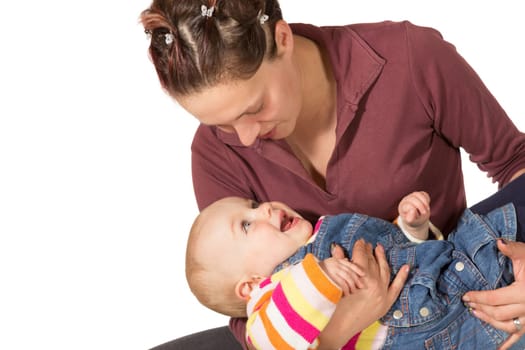 Attracive young mother cradling a laughing baby in her arms who is looking at her with innocent love and trust