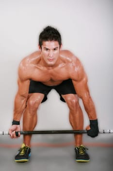 Young man lifting the barbell in the gym.
