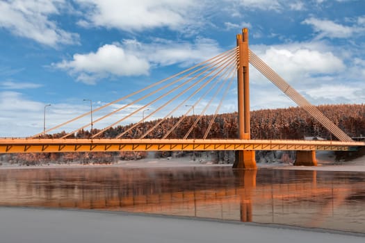 The bridge over the river against the backdrop of winter snow-covered forest