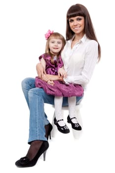 beautiful mother with a cute daughter sitting on a chair in the studio on a white background