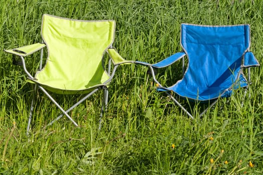 Two empty folding chair on the green grass on a sunny day