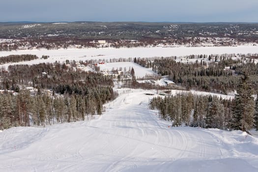 View on empty fresh-made downhill ski slope and mountains on a sunny day
