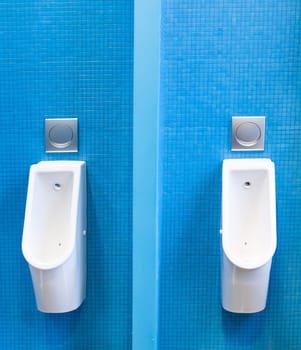 Modern urinals on the blue tiled wall