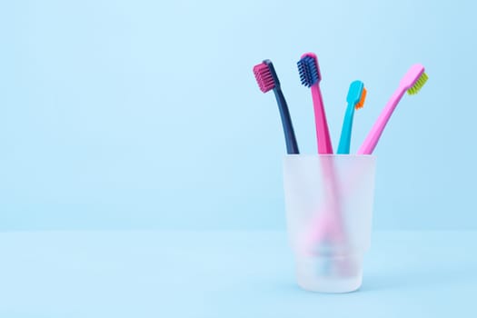 Four toothbrushes - dental hygiene. Selective focused on front toothbrush, blue background.