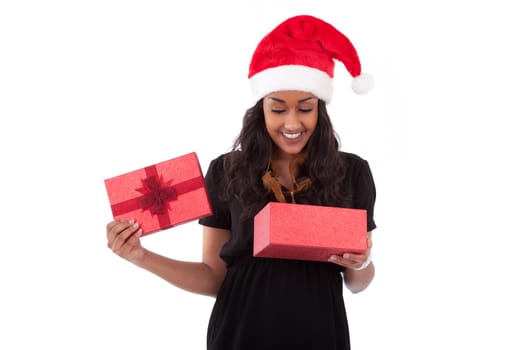 Young African American woman wearing a santa hat opening a gift box, isolated on white background