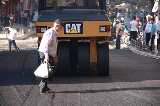 old man walking on asphalt while they constructing in Turkey