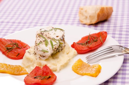 Roasted monkfish on a plate with tomatoes and peppers