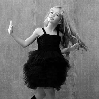 black dress kid girl dancing and twisting on vintage background