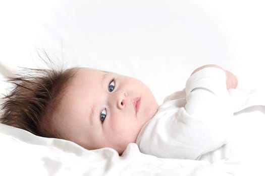 Portrait of a baby 4 months old lying down with mohawk hairstyle.