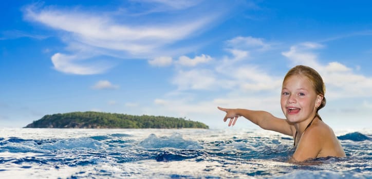 girl in the sea pointing to an island at the horizon