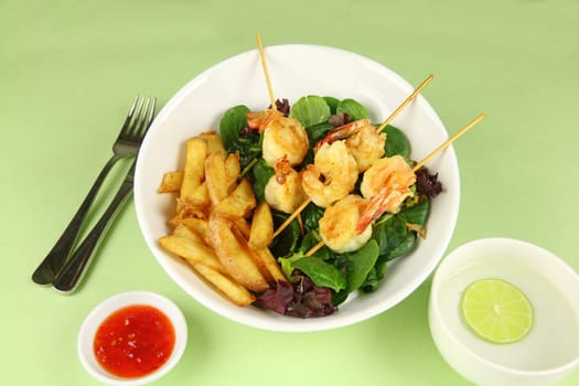 Yummy fried shrimp skewers with chunky chips with sweet chilli sauce ready to serve.