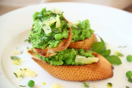 Delicious green pea baguettes with shaved cheese and mint with avocado oil.