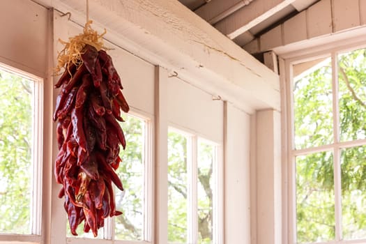 Dried red chili peppers hanging in front of a window