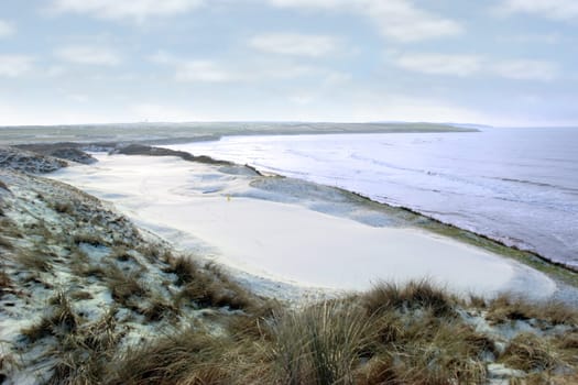 atlantic ocean beside a snow covered links golf course in ireland in snowy winter weather