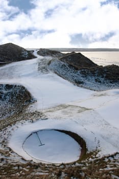 a rake in a bunker on a snow covered links golf course in ireland in snowy winter weather