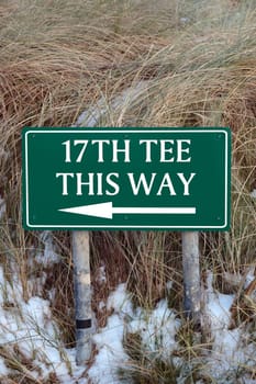 the 17th tee this way sign on an irish golf course in the winters snow