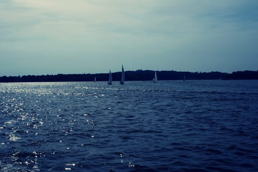Segelboote bei Gegenlicht auf einem See fotografiert.