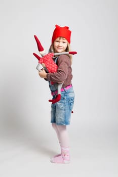 Studio portrait of happy smiling young girl holding Christmas elf doll in standing