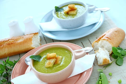 Delicious bowls of pea soup with fresh mint and crusty bread.