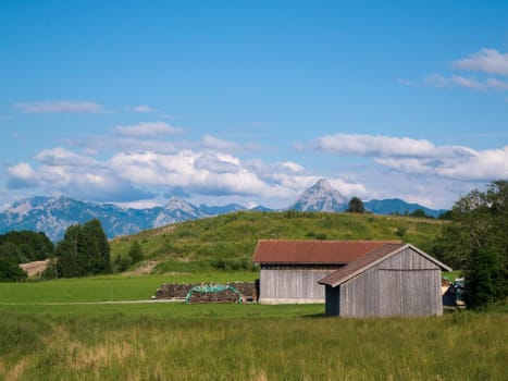 Landscape shot with two hay huts in the Ostallgäu near the town of Pfronten in the summer of 2012 under blue skies with scattered cumulus clouds