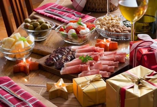 Full table of prosciutto, olives, cheese, salad and wine for holidays