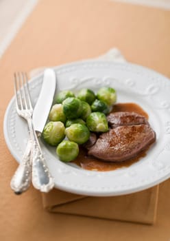 Deer steak with brussel sprouts and sauce close up