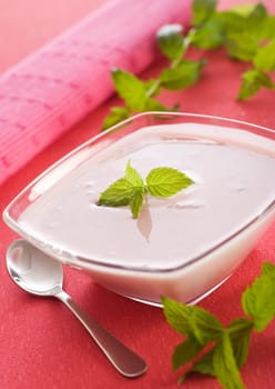 a bowl with yogurt on pink background close up