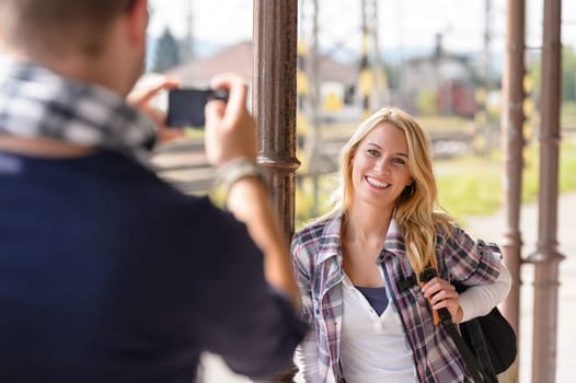 Woman smiling man taking her picture vacation backpack railroad camera