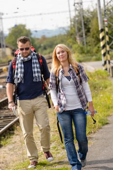 Couple walking with backpack in train station happy woman man