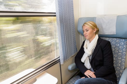 Woman asleep in train compartment tired resting commuter sleeping trip