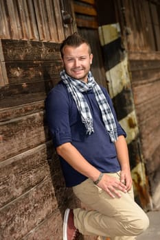Man posing leaning against wooden wall fashion smiling lifestyle leisure