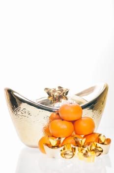 A stack of tangerine with large ingot as background