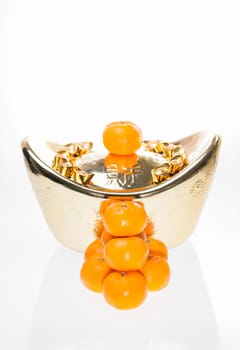 A stack of mandarin oranges with large ingot as background