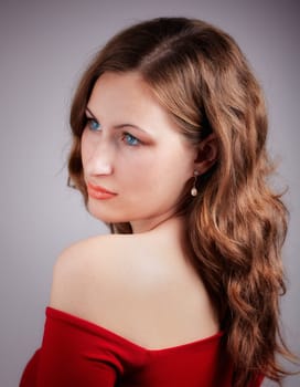 Studio portrait of a beautiful 20 year old redhead woman with red dress.