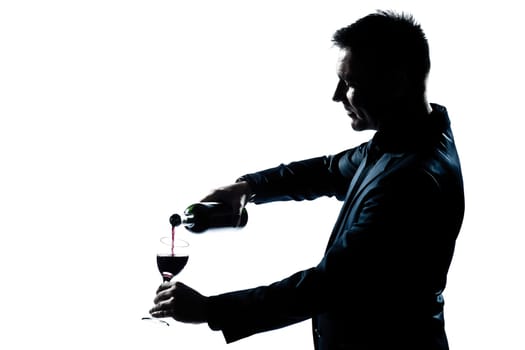 one caucasian man portrait pouring wine in a glass silhouette in studio isolated white background