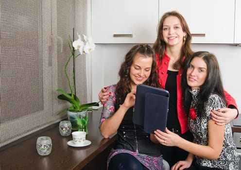 Women friends chatting at home and using laptop to look at new photo or browsing internet for information
