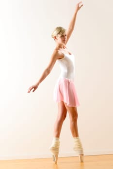 Beautiful ballerina on tiptoe with raised arm dancing pointe