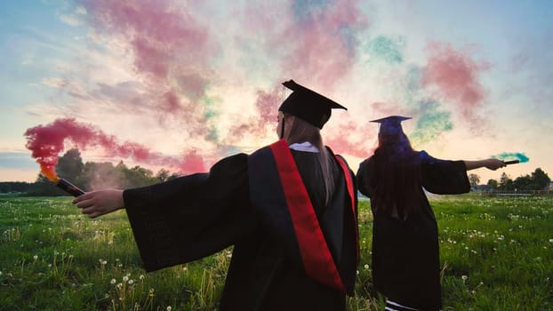 Students graduate with colored smoke walking through the meadow in the evening