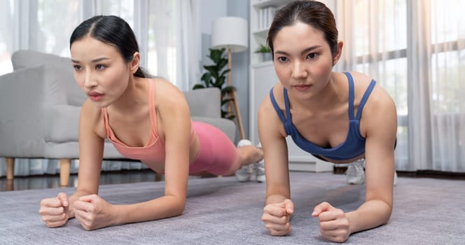 Fit young asian woman planing on the living room floor with her trainer or exercise buddy. Healthy lifestyle workout training routine at home. Balance and endurance exercising concept. Vigorous