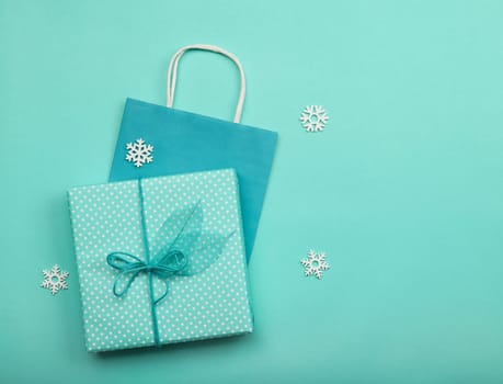 Close up teal blue wrapped giftbox and paper gift bag on table, table top view, flat lay