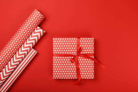 Close up packing and wrapping gifts with red and white paper, table top view, flat lay