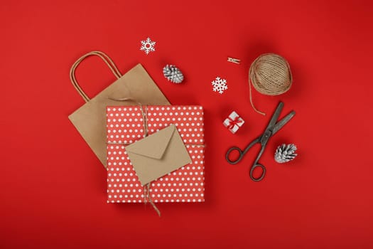 Close up packing and wrapping Christmas gifts with red and brown paper, table top view, flat lay