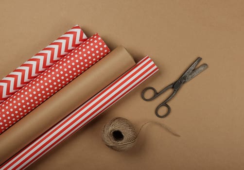 Close up packing and wrapping gifts with red and brown paper, table top view, flat lay
