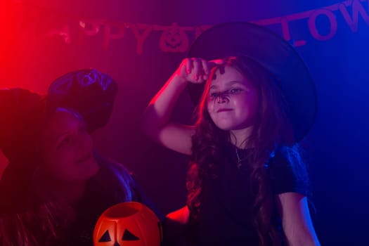 Funny child girl and woman in witches costumes for Halloween with pumpkin Jack and dog